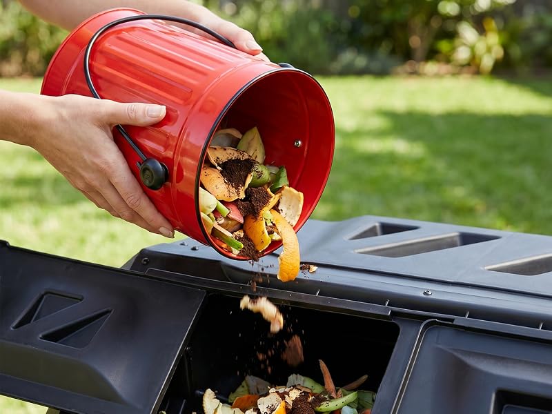 Red compost bin being emptied into an outdoor compost bin